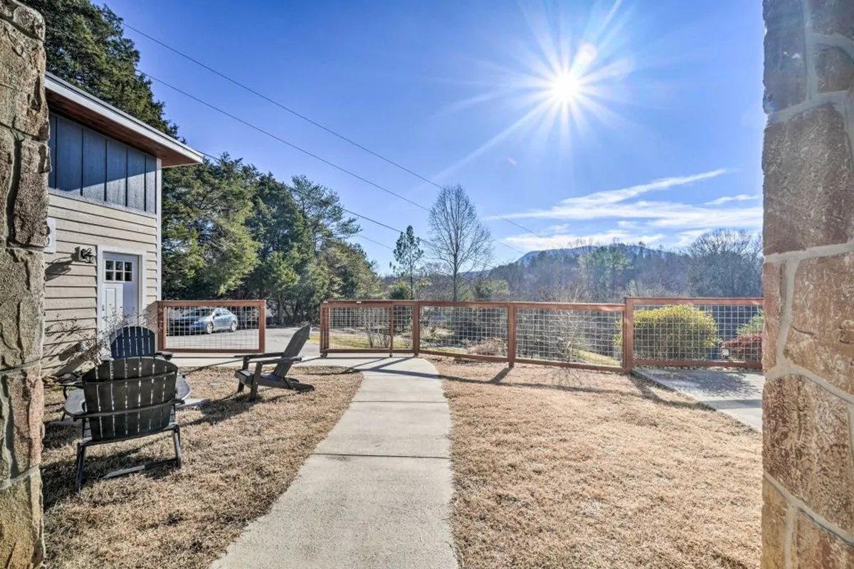 A cluster of Adirondack chairs faces out towards a fenced yard and distant mountains, bathed in soft sunlight. This peaceful spot is ideal for fireside chats, group gatherings, or simply enjoying the serenity of the landscape.