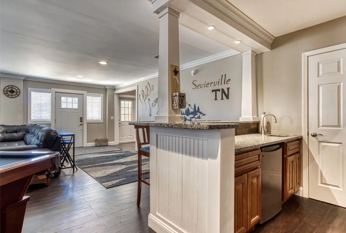 A view of the kitchen area featuring a granite countertop, kitchen cabinetry, and an entryway with decorative wall art. The scene feels welcoming and is well-suited for both meal prep and entertaining guests.