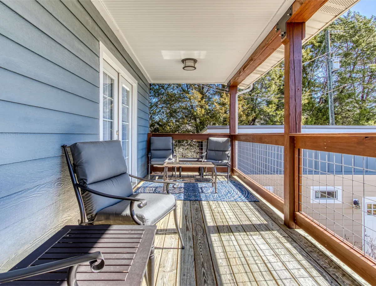 A private deck featuring elegant seating, a decorative rug, and a wooden railing overlooks the tranquil natural surroundings. The setup is inviting, perfect for relaxing with a coffee or sharing a quiet moment while taking in the fresh mountain air.