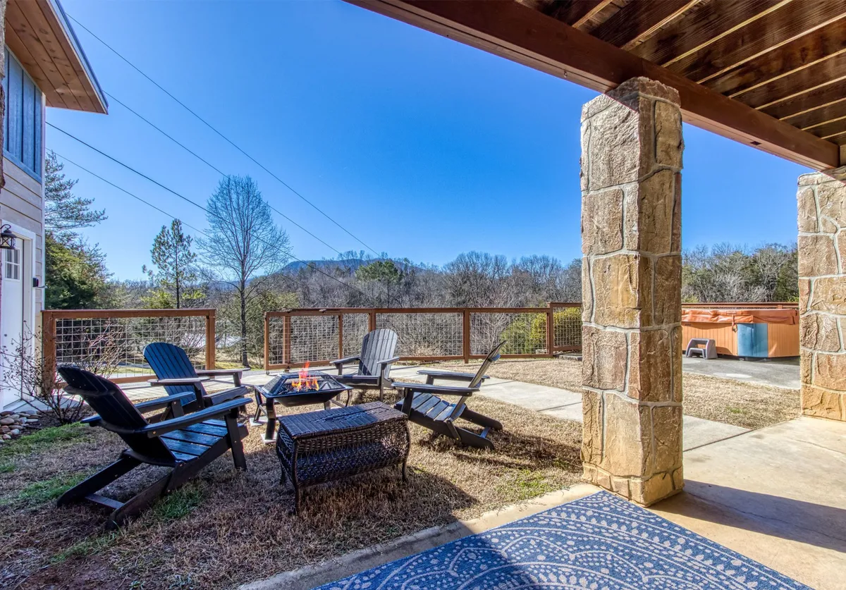 This exterior shot centers on a stone fire pit surrounded by Adirondack chairs, with a stunning mountain view in the background. The arrangement invites guests to gather, share stories, and watch the sunset or enjoy cozy evenings by the fire.