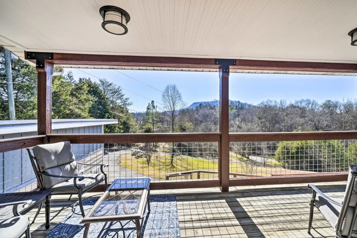 A spacious deck furnished with outdoor furniture provides ample space for gathering, set against a panoramic mountain view. The area is perfect for socializing, sipping coffee, or hosting outdoor meals while appreciating the natural surroundings.