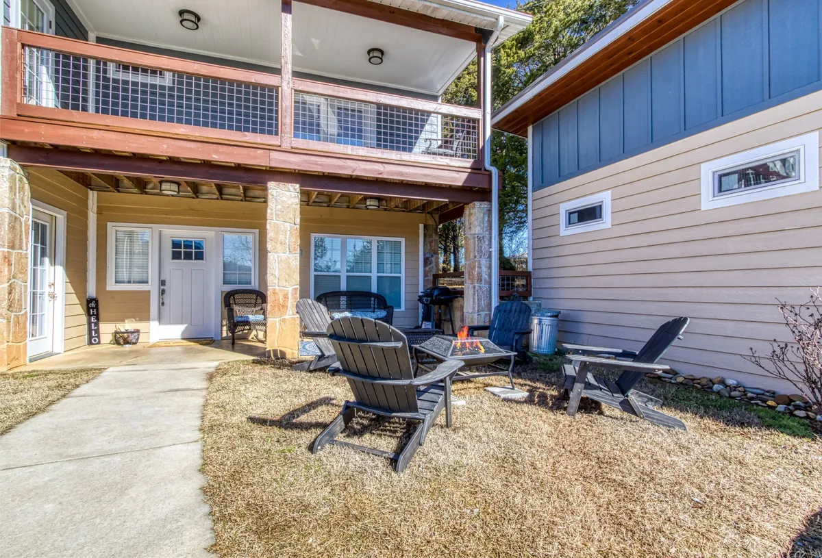 A welcoming exterior shot showing a fire pit surrounded by Adirondack chairs and a cozy porch with a railing. This scene invites evening gatherings, storytelling, and making s'mores under the stars—the exact family-friendly amenities highlighted in the section.