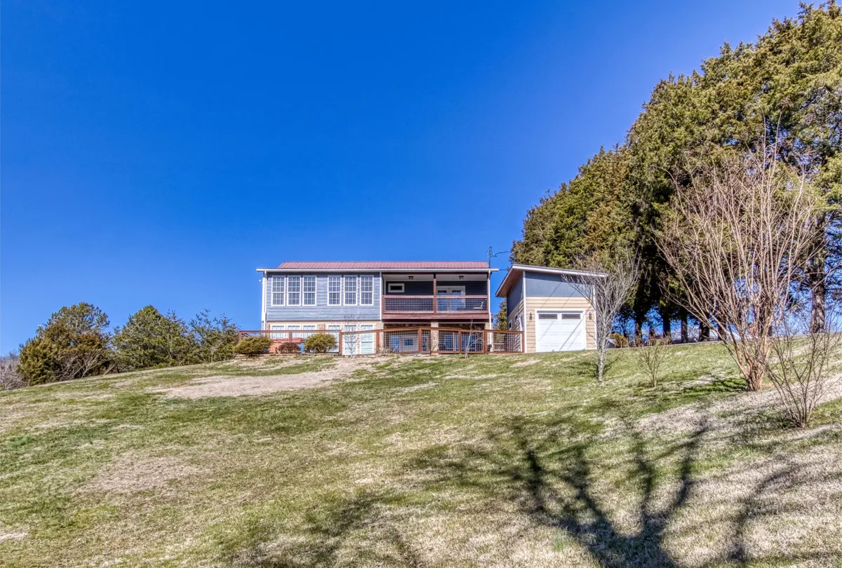 A serene exterior shot showcasing the home, its garage, and surrounding landscaped grounds. The scene is bathed in natural light, suggesting a peaceful retreat after a day outdoors. The setting invites guests to relax and enjoy the beauty of the natural environment from the comfort of their accommodations.